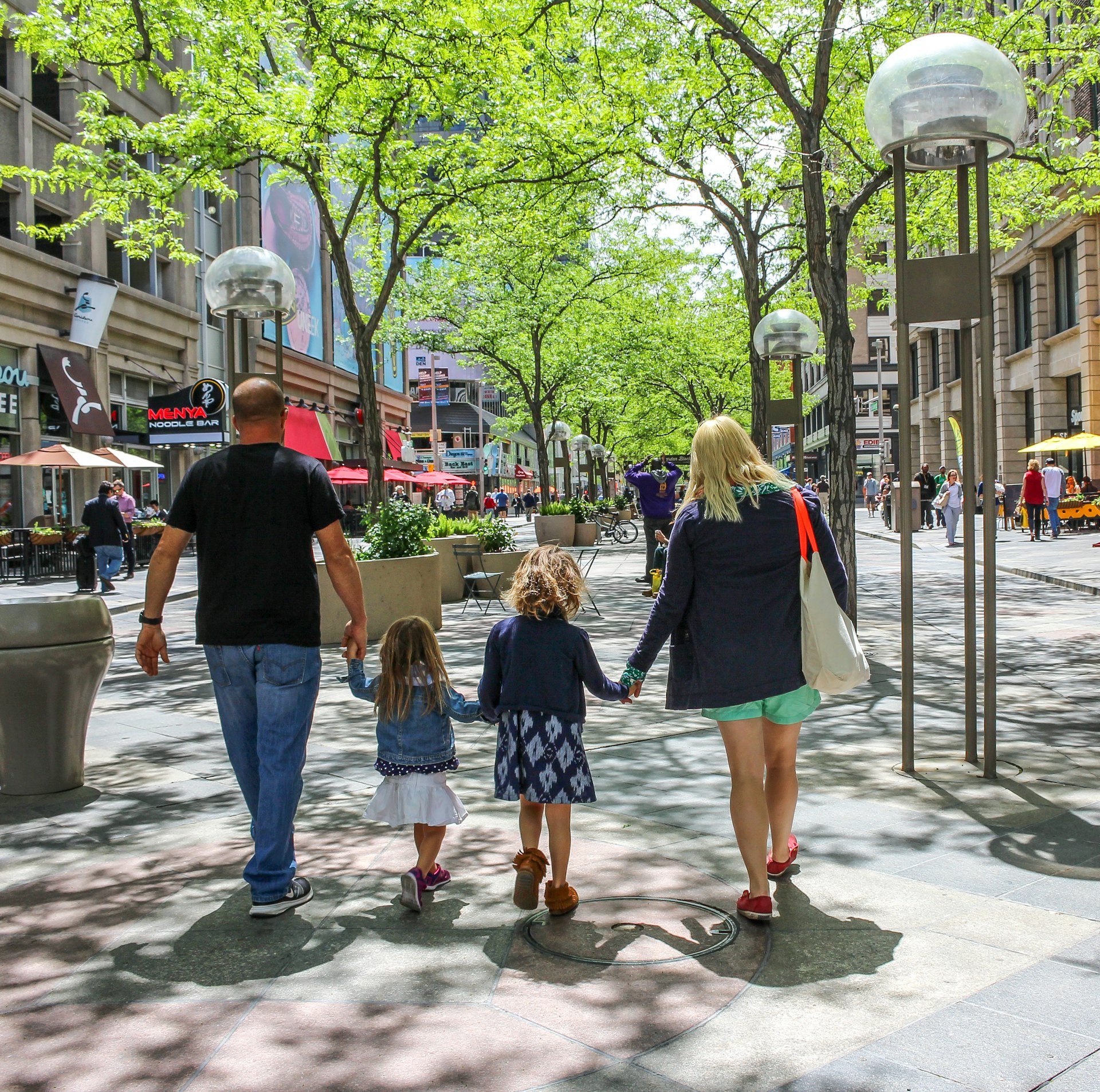 A rear view of a family of four as they walk along the street in downtown Denver